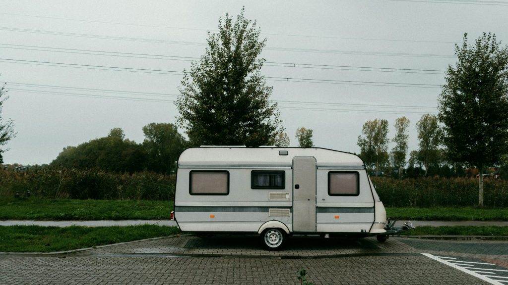 Une caravane vintage garée dans un cadre extérieur serein, au milieu d'une végétation luxuriante.